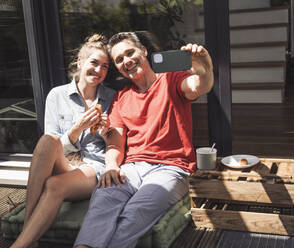 Couple taking selfie while relaxing on balcony - UUF30109