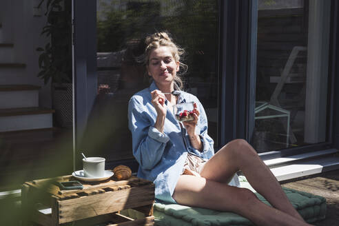 Portrait of a woman enjoying dessert on balcony - UUF30117