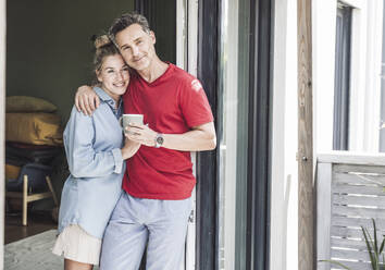 Couple standing together by open balcony - UUF30123