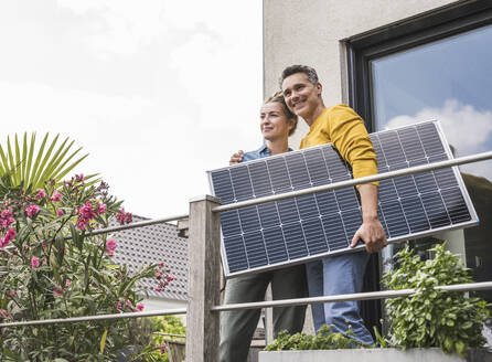 Couple standing on balcony with unmounted solar panel - UUF30172