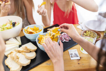 Freunde essen Nacho-Chips und Brot am Tisch - JPTF01278