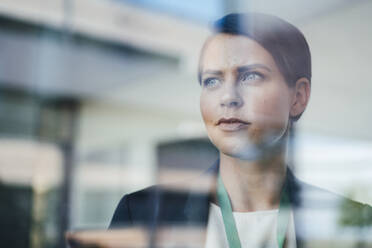 Thoughtful businesswoman seen through glass in office - JOSEF20702