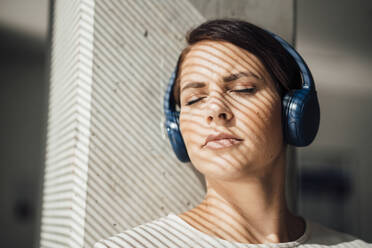 Geschäftsfrau mit geschlossenen Augen, die über drahtlose Kopfhörer Musik hört - JOSEF20723
