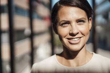 Smiling businesswoman with short hair in office - JOSEF20746