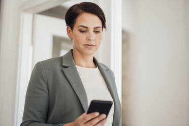 Businesswoman using mobile phone at office - JOSEF20794