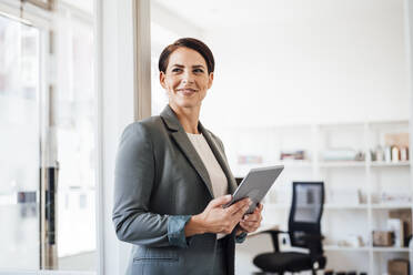 Smiling businesswoman with tablet computer in workplace - JOSEF20804