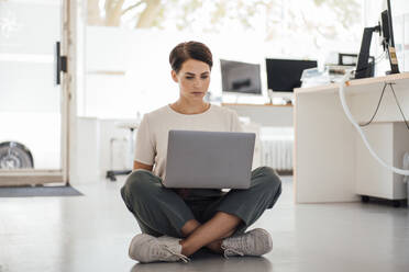 Businesswoman working on laptop sitting at workplace - JOSEF20813