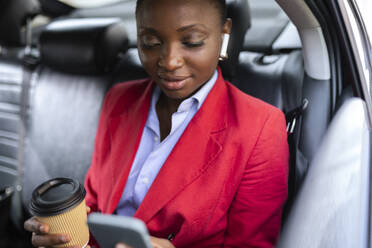 Lächelnde Geschäftsfrau mit Smartphone im Auto - JPTF01289