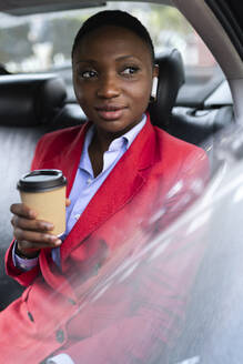 Thoughtful businesswoman with coffee cup sitting in car - JPTF01290