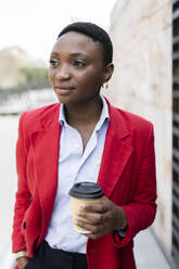 Contemplative businesswoman standing with coffee cup - JPTF01293