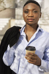 Geschäftsfrau stehend mit Kaffeetasse an einem sonnigen Tag - JPTF01301