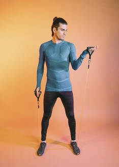 Athlete exercising with resistance band in front of backdrop - MMPF00863