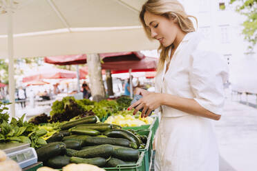 Lächelnde Frau beim Kauf von frischem Gemüse auf dem Bauernmarkt - NDEF00995