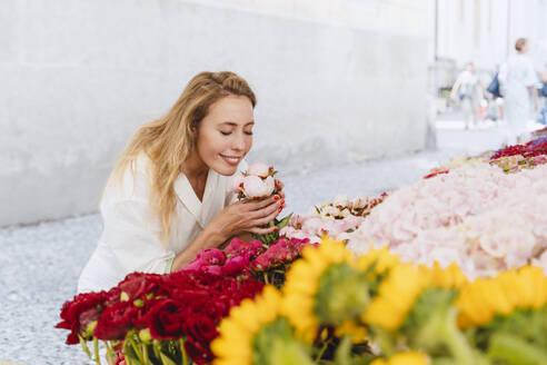 Lächelnde Frau riecht an Blumen auf dem Markt - NDEF01051