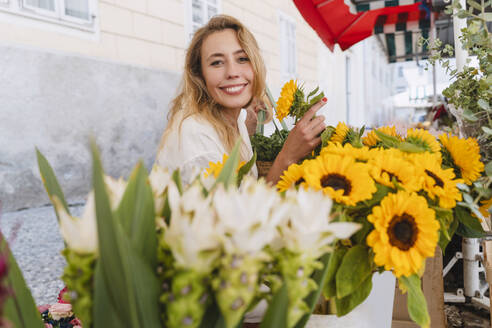 Glückliche Frau kauft gelbe Sonnenblumen auf dem Markt - NDEF01055