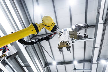 Yellow robotic arm with machine under ceiling in factory - AAZF00938