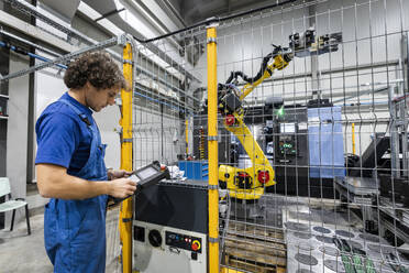 Techniker, der einen Roboterarm mit Maschinen in einer Fabrik bedient - AAZF00943