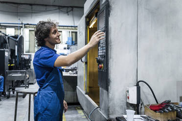 Lächelnder Techniker, der eine CNC-Maschine in der Metallindustrie bedient - AAZF00964