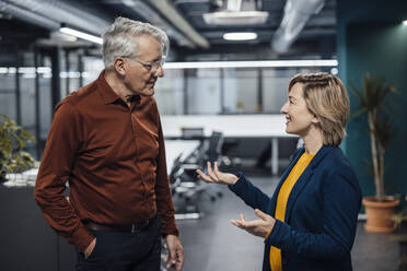 Smiling businesswoman gesturing and discussing with colleague in office - JOSEF20881