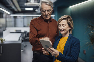 Business colleagues discussing over tablet PC at work place - JOSEF20882