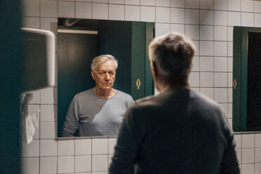 Senior man looking in mirror in bathroom - JOSEF20896