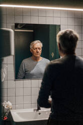 Senior man looking in mirror in bathroom - JOSEF20898