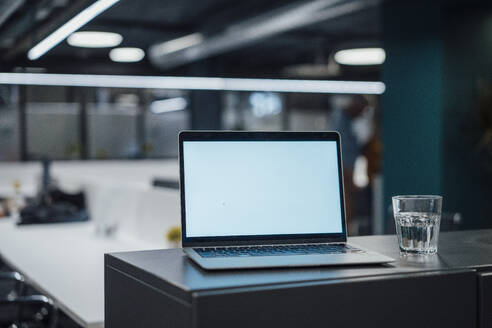 Laptop und Glas Wasser auf dem Schreibtisch im Büro - JOSEF20950