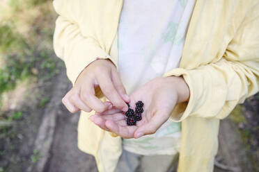 Boy with blackberries standing in forest - EYAF02770