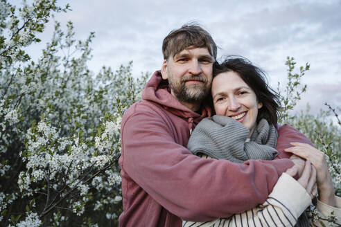 Smiling couple standing in front of plants - EYAF02790