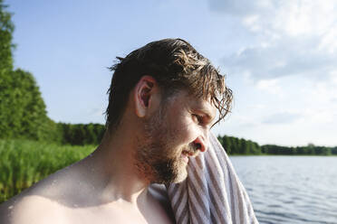 Mann wischt sich die Haare mit einem Handtuch am See ab - EYAF02796