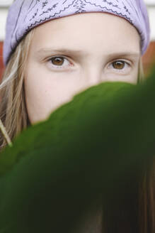 Girl wearing headband hiding face with leaf - EYAF02802
