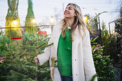 Contemplative woman standing near Christmas tree at market - MDOF01463