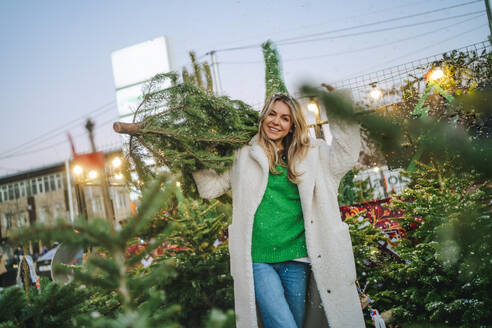 Glückliche Frau mit Weihnachtsbaum auf dem Markt - MDOF01471