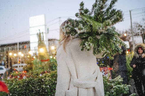 Blonde Frau mit Weihnachtsbaum auf dem Markt - MDOF01477