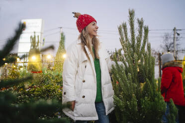 Happy woman standing near Christmas tree at market - MDOF01484