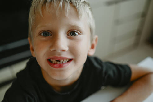 Lächelnder Junge mit Zahnlücke zu Hause - ANAF02104