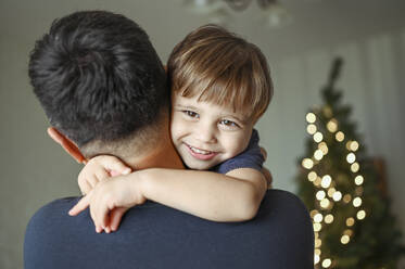 Father embracing smiling son at home - ANAF02112