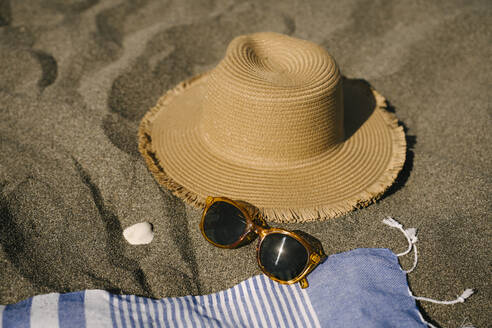 Sun hat next to sunglasses on sand at beach - YBF00201