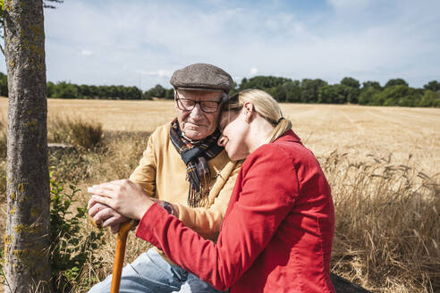 Woman leaning on elderly man's shoulder on sunny day - UUF30191