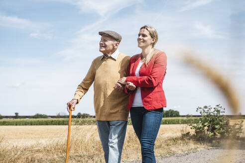 Happy woman holding hand of senior man on sunny day - UUF30204