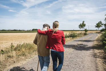 Frau mit Arm um älteren Mann geht durch Feld - UUF30208