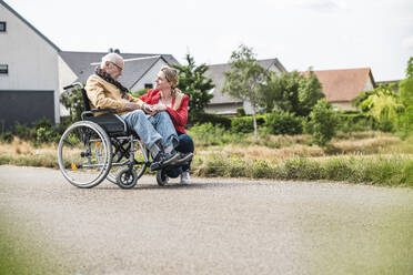 Frau im Gespräch mit älterem Mann, der im Rollstuhl auf der Straße sitzt - UUF30249