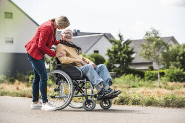 Woman talking with elderly man sitting in wheelchair - UUF30252