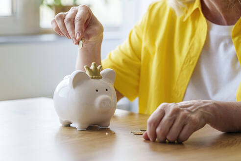 Senior woman saving money in piggy bank - AAZF01021