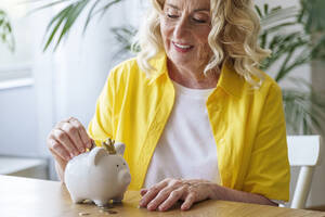 Glückliche ältere Frau spart Geld im Sparschwein - AAZF01022
