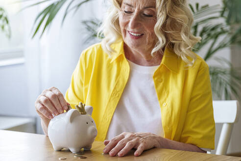 Happy senior woman saving money in piggy bank - AAZF01022