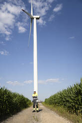 Engineer standing in front of wind turbine on sunny day - EKGF00481
