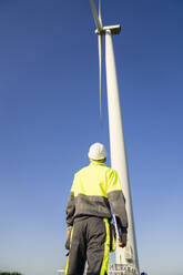 Engineer examining wind turbine on sunny day - EKGF00498