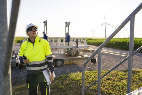 Engineer wearing hardhat examining wind turbines - EKGF00510