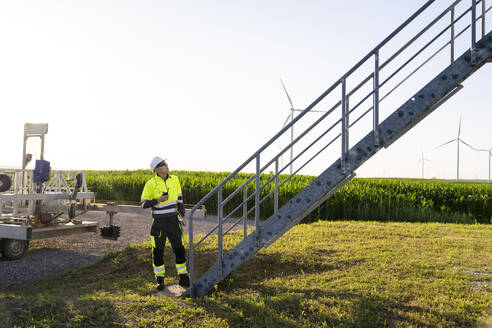 Engineer wearing hardhat standing by staircase - EKGF00511